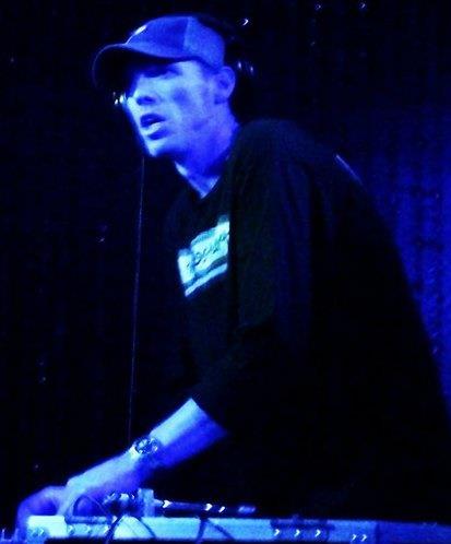 DJ Natural Nate® on Pioneer decks bathed in deep blue stage lighting